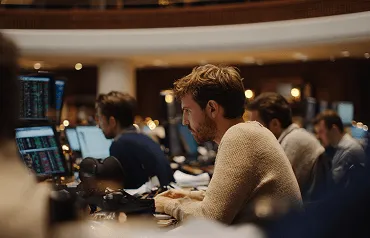 Profissional concentrado diante de múltiplos monitores em uma mesa de operações financeiras.