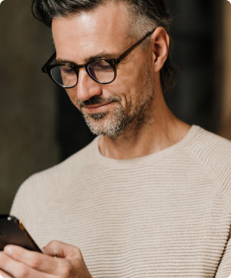 Homem sorrindo enquanto usa o celular.