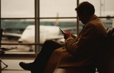 Homem utilizando o aplicativo Avenue enquanto espera para embarcar em um aeroporto